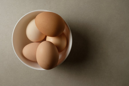 Fresh farm eggs nestled in a bowl on a rustic table settingの写真素材