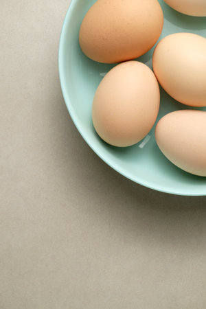 Fresh eggs resting in a light blue plate on a neutral backgroundの写真素材