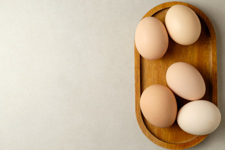 Freshly collected eggs displayed on a wooden tray in soft morning light