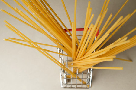 Colorful spaghetti sticks fill a shopping basket on a simple background