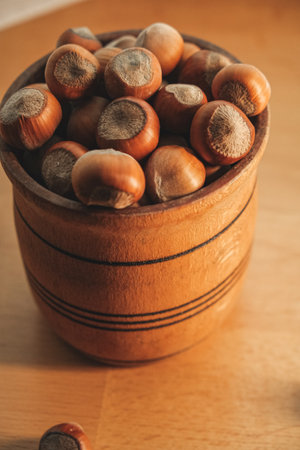 Beautiful wooden bowl filled with fresh hazelnuts on a tableの写真素材