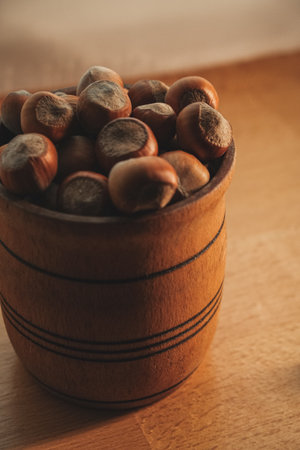 Wooden bowl filled with fresh hazelnuts resting on a wooden surfaceの写真素材