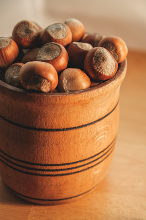Freshly harvested hazelnuts in a rustic wooden bowl on a wooden tableの写真素材