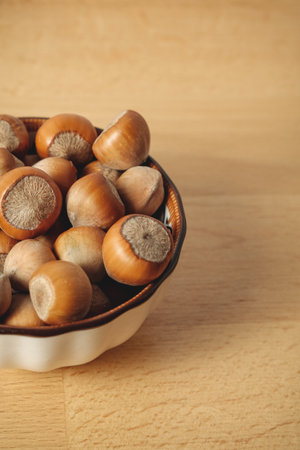Freshly harvested hazelnuts in a rustic bowl on a wooden tableの写真素材