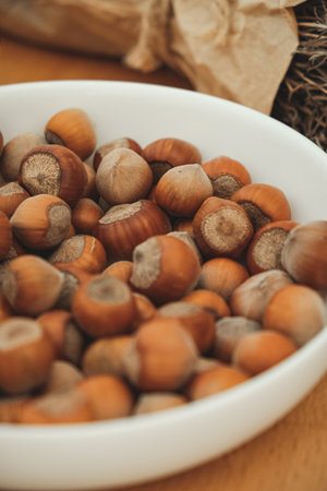 Unique collection of hazelnuts in a rustic bowl on a wooden surfaceの写真素材