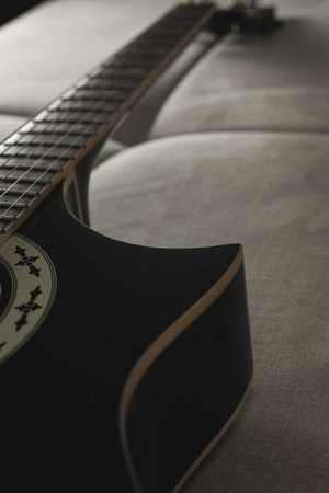 Strumming a beautiful black guitar on a cozy couch in soft evening lightの写真素材