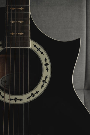 Beautiful acoustic guitar resting on a cozy gray sofa in a music studioの写真素材