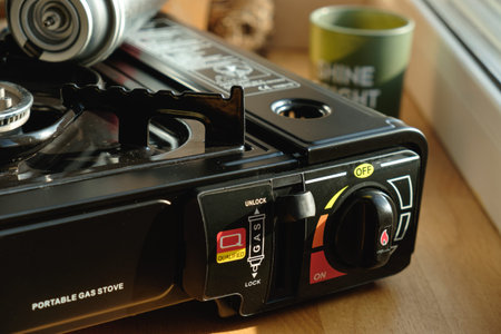 Portable gas stove resting on a wooden countertop near a sunny windowの写真素材