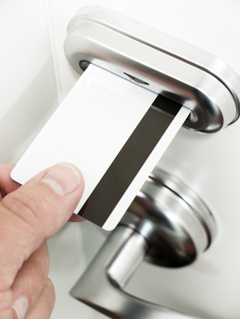 A person's hand unlocking a hotel room keycard door lock by inserting a magnetic stripe key cardの写真素材