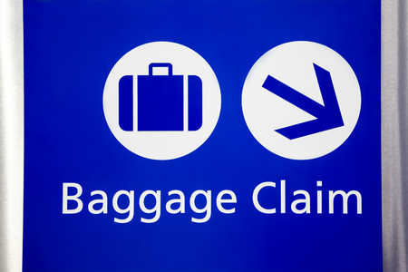 Blue airport baggage claim sign with suitcase and arrow symbols.の写真素材