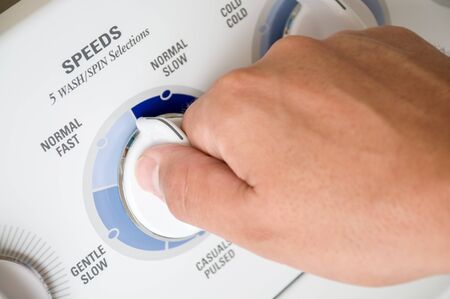 Washing machine dial being turned by a male hand