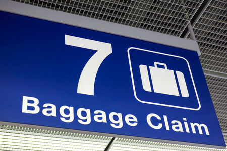 A blue airport baggage claim sign hanging from the ceilingの写真素材