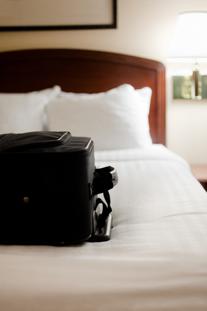 Picture of a black suitcase on a hotel room bedの写真素材