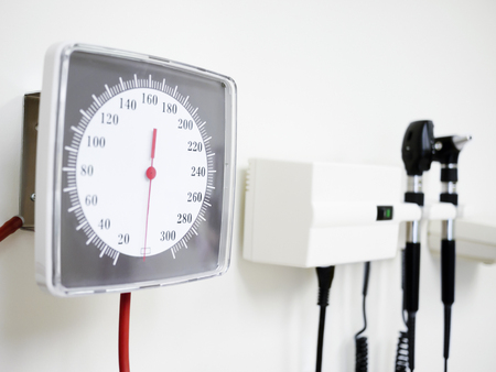 Sphygmomanometer blood pressure gauge, otoscope ear scope and ophthalmoscope eye scope hanging on a doctor's office wallの写真素材