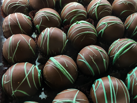 Round chocolate candies with green topping in rowsの写真素材