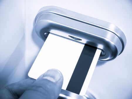 Person's hand inserting a magnetic stripe keycard into a hotel room electronic keycard door lockの写真素材