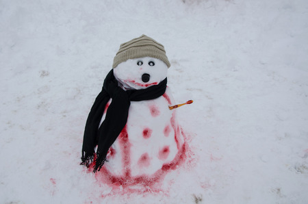 Closeup of smiling snowman with woolen hat, scarf and  outdoors in snowfallの写真素材