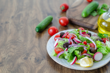 Healthy vegetable salad is  on a white plate on a wooden table, top viewの写真素材
