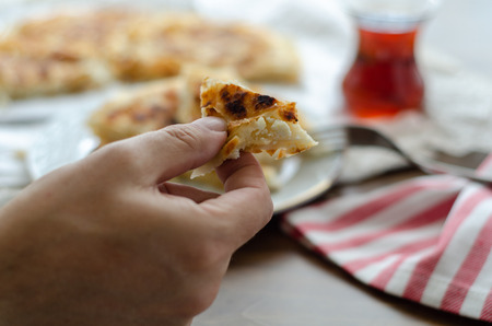 A man is holding a slice of cheese pie in his hand.の写真素材
