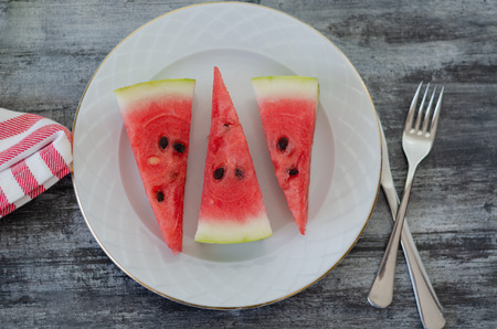 Sliced watermelon on white dish on wood background.Ready for service.の写真素材