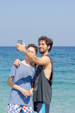 Two brothers are making selfie on the beach in summer.の写真素材