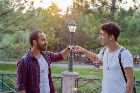 Two men bumping their fists together, greetings. They are meeting at the parkの写真素材