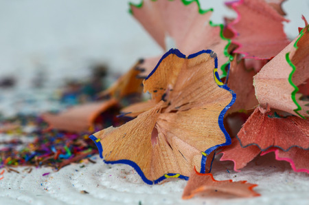 Shavings of sharpening colorful  pencils  on white table, close up