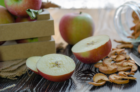 Delicious fresh red apples  and slices of dried apple are on the wooden table.の写真素材
