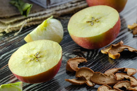 Delicious fresh red apples  and slices of dried apple are on the wooden table.の写真素材