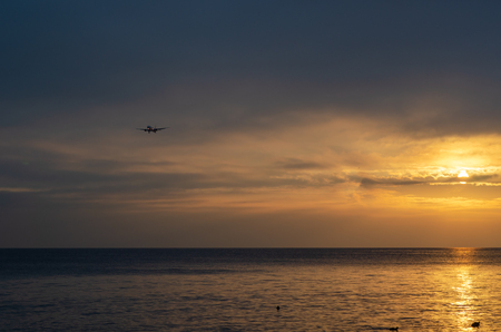 A airplane flying in the sky at sunset.Sky is cloudy and dramatic.の写真素材