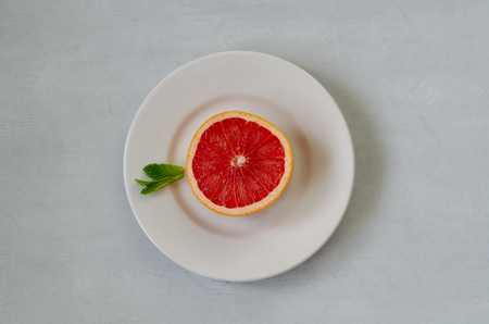 A slice of grapefruit on a white plate, top view.の写真素材