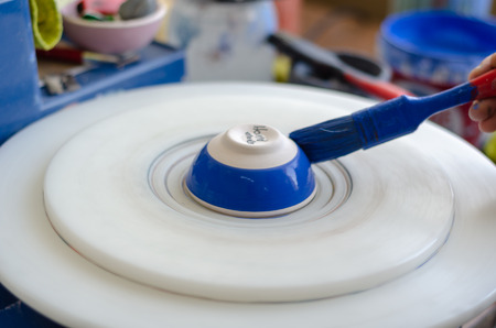The ceramist hands is painting  a blue ceramic bowlの写真素材