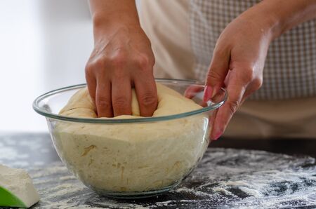 Woman is kneading dough on kitchen table, closeupの写真素材