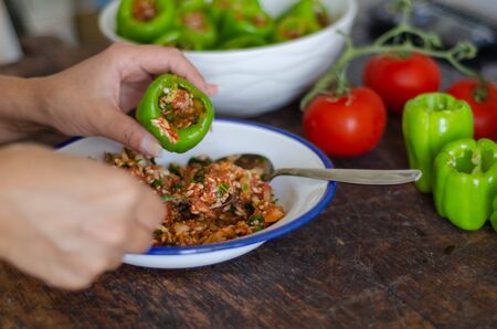 Woman is filling  with rice and meat the green pepper. Turkish cuisine food the stuffed pepper.