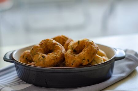 Traditional Turkish pastry : PiÅŸi ; fried dough in oil with dill in tray on wooden table.