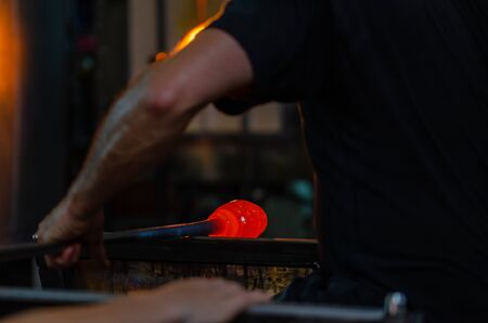 Glass blower manufacturing process, moment of shaping the glass  at a glass makers workshop