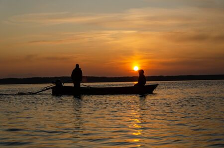 Silhouette of fishing boat and fisherman  in the sunrise on the lake in the sunrise .の写真素材