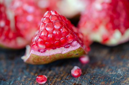 Red and juicy pomegranate seeds  on wooden table.のeditorial素材