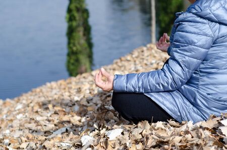 The  woman is yoga meditating and making zen symbol on autumn leaves on the outdoors.の写真素材