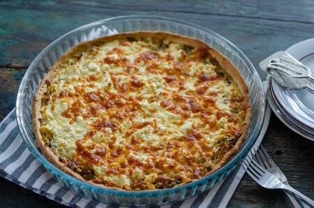 The filled pie with leek and cheese on the wooden table.