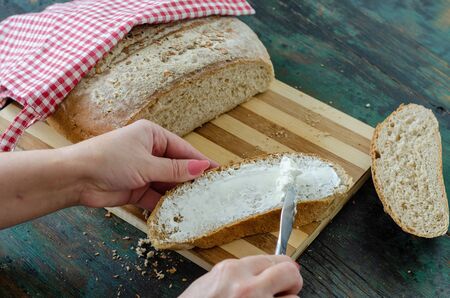 woman is taking cheese to bread on the wooden table