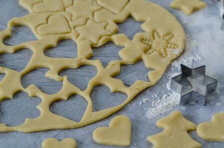 Preparing Christmas cookies using cookie cutters and a rolling pin.  Selective focus on the cutter and cookie doughの写真素材