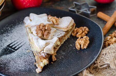 Slice of fresh baked homemade apple pie and walnuts on the black plateの写真素材