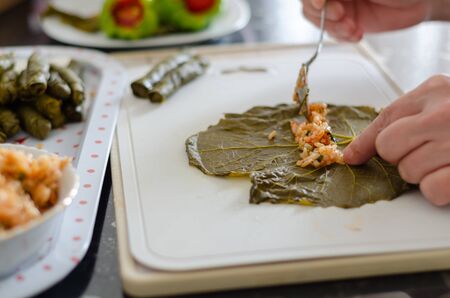 Traditional Turkish Dolma or Sarma.  The woman is stuffing grapes leaves on the white backgroundの写真素材