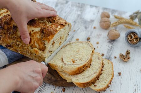 The woman is cutting the fresh bread in the kitchen, top view.の写真素材