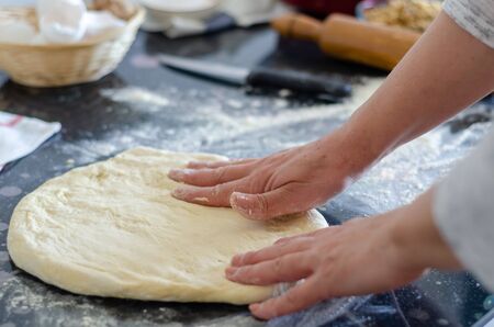 Hands kneading dough for pizza or bread  on the black  background, close-up