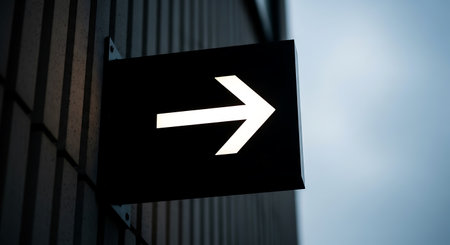 A black sign with a glowing white arrow pointing right is mounted on a textured wall. The background is a soft blue.の素材