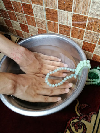 Hands in a bowl of water with rosary beads.の写真素材