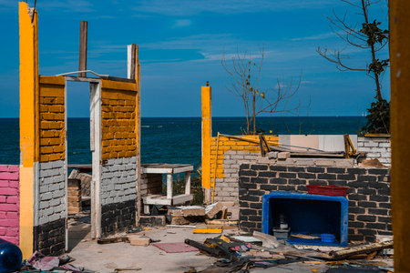crumbling remains of a demolished brick structure against a deep blue ocean and bright sky.