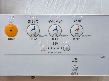 Close-up of a Japanese bidet control panel with Braille, featuring buttons for spray, soft wash, stop, and water pressure adjustments.の写真素材